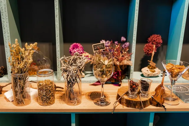 A shelf with jars of herbs, dried flowers and a decorated cocktail glass