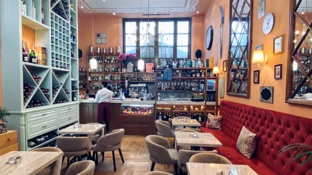 A hall with a red velvet sofa, marble tables, a wine rack and a designed bar counter