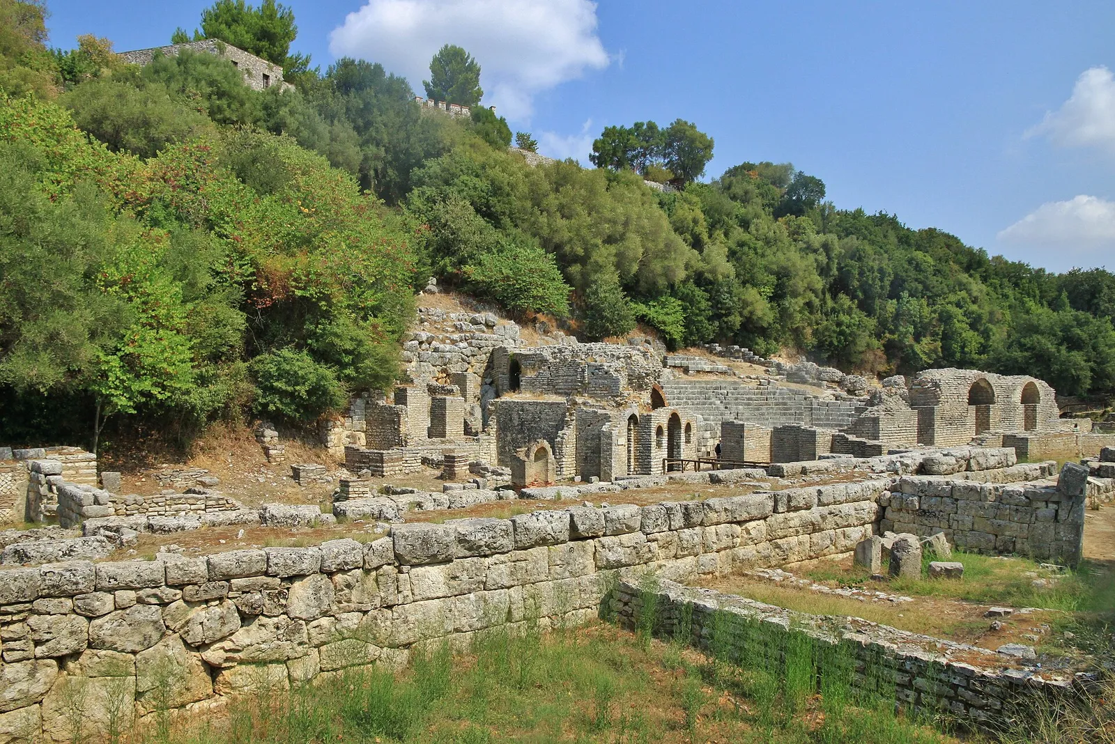 Stone walls and arched ruins of the ancient city of Butrint surrounded by greenery near Ksamil